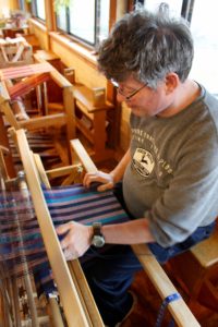 Mitch works independently at his loom to create hand-woven placemats